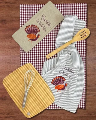 Thanksgiving kitchen gift set with a cutting board, tea towels, whisk and wooden utensils