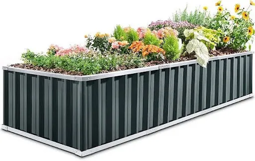 Long dark green metal raised garden bed planted with mixed flowers