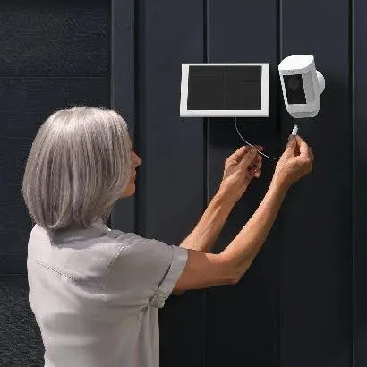 Woman installing a video doorbell beside a dark front door