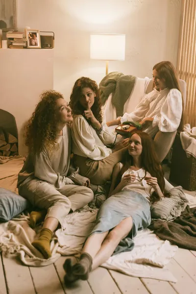 Group of women relaxing together on a bedroom floor among blankets